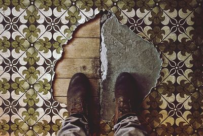 Low section of man standing on torn carpet