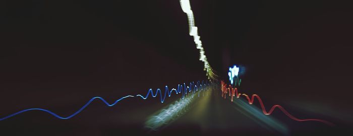 Low angle view of light trails against sky at night