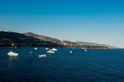 Sailboats sailing in sea against clear sky