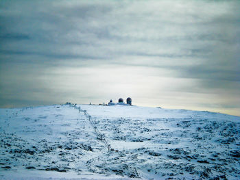 People on snow covered land against sky