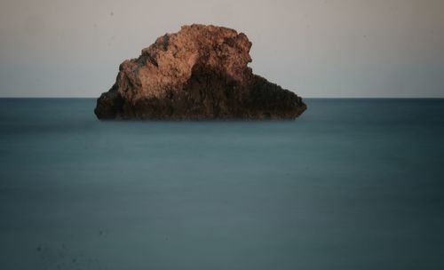 Close-up of rock in sea against sky