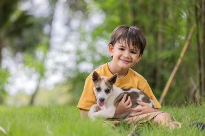 Portrait of cute boy with dog against plants