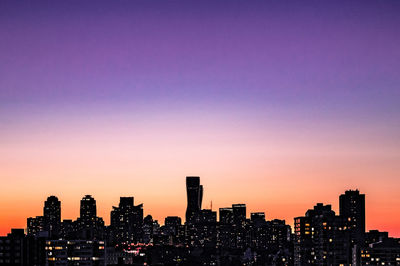 Illuminated skyline against sky during sunset