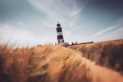 Lighthouse on field against sky