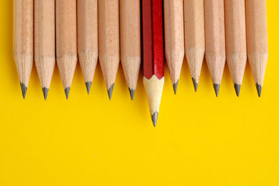 High angle view of colored pencils against yellow background
