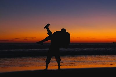 Silhouette of people on beach at sunset