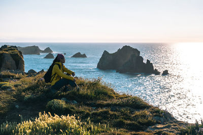 Asian girl sitting after hiking along the coast in spring during the sunset