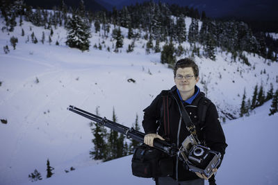 Mature man with backpack and tripod standing on snow