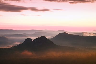 Scenic view of silhouette mountains against orange sky