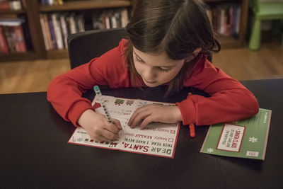 Cute girl writing letter to santa claus at home during christmas