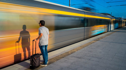 Rear view of man standing on train at railroad station platform