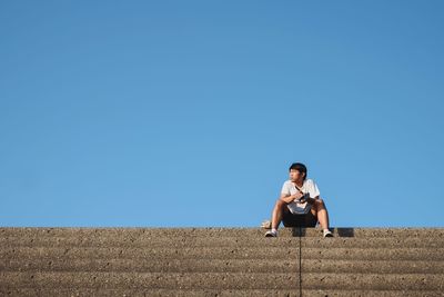 Side view of young men standing against clear sky