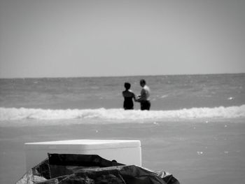People standing on beach against clear sky