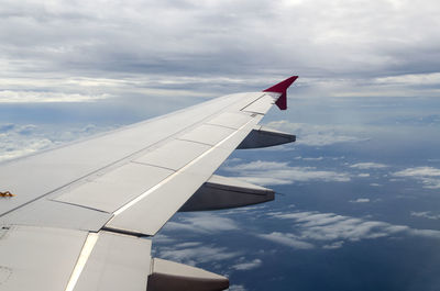 Cropped airplane wing flying against sky