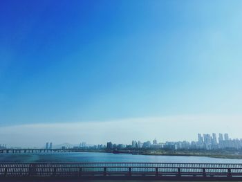 City by river against clear blue sky