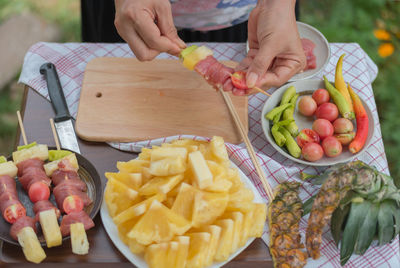 Cropped image of hand putting food in skewer