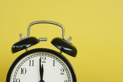 Close-up of alarm clock against yellow background