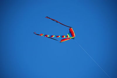 Low angle view of kite against clear blue sky