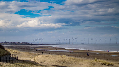 Traditional windmill by sea against sky