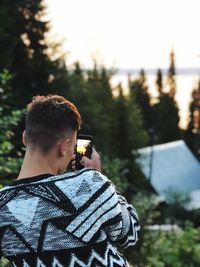 Rear view of man photographing during sunset