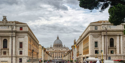 Buildings in city against cloudy sky