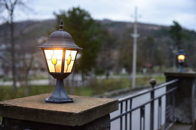 Illuminated street light against sky at dusk
