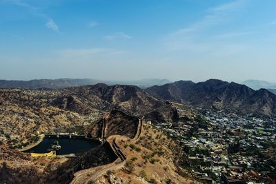 High angle view of cityscape by mountains against sky