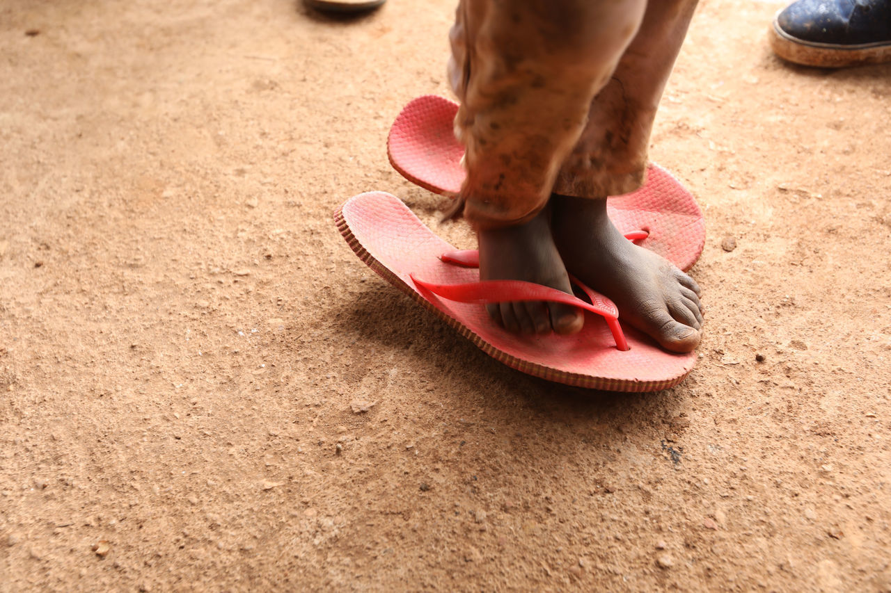 LOW SECTION OF WOMAN WEARING HIGH HEELS ON FOOTPATH