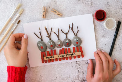 Diy merry christmas deer on greeting card postcard made of pebbles, sea stones, clothespins 