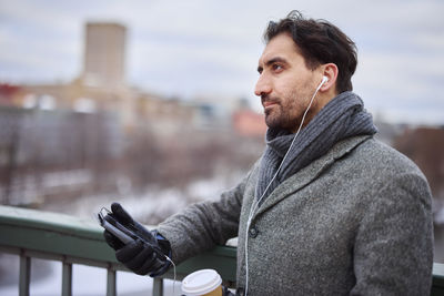 Elegant man with smartphone and paper cup on footbridge