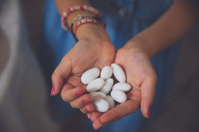 Midsection of woman holding white pebbles at home