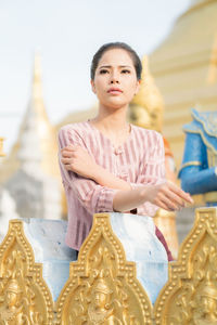 Young woman looking away while standing by railing