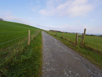 Road amidst field against sky