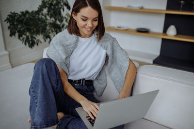 Portrait of young woman using laptop at home