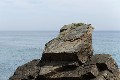 Rock formation by sea against sky