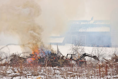 Tractor moves brush during a controlled burn on a farm to make more arable land