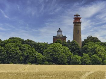 Lighthouse by field against sky