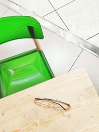 High angle view of eyeglasses on table with green chair at restaurant