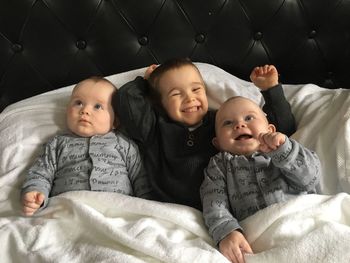 Happy siblings lying on bed at home