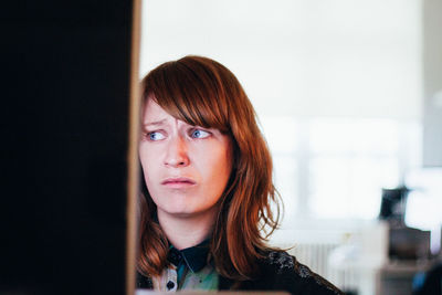 Close-up of worried woman while sitting at computer desk in office