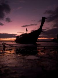 Silhouette sailboat on beach against sky during sunset