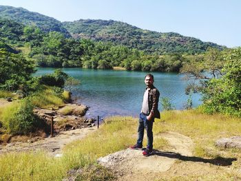 Portrait of man standing by lake against trees