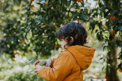 Side view of girl holding orange in farm
