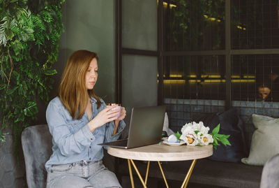 Young woman using mobile phone while sitting at home