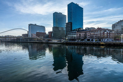 Buildings by river against sky in city