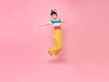 Full length of a man jumping over pink background