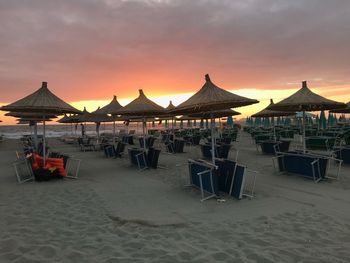 Chairs on beach against sky during sunset