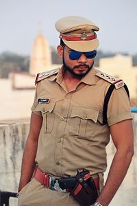 Policeman wearing sunglasses standing against sky