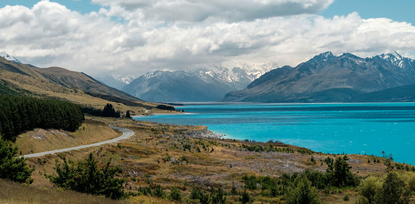 Scenic view of turquoise lake pukaki and mountains against dramatic sky
