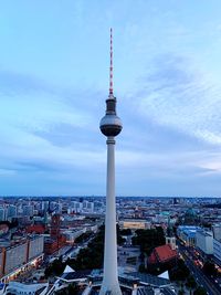 Communications tower in city against sky